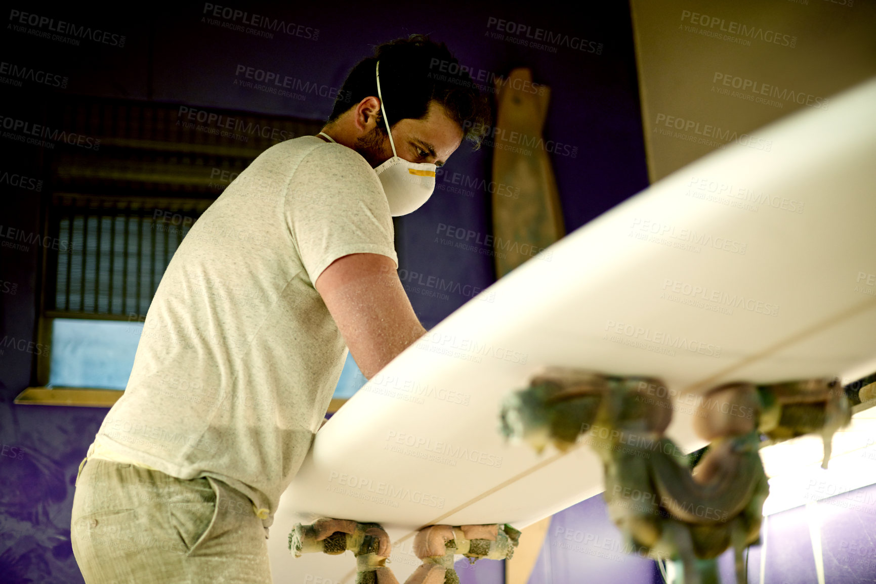 Buy stock photo Surfboard, craft and man with mask in workshop for manufacturing, custom design and shape material. Entrepreneur, handmade production and person with foam plank, safe construction or repair in studio