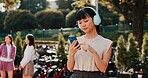 Headphones, phone and college with Japanese woman in park for streaming, University campus and online playlist. Music, radio and education podcast with person and mobile in Japan outdoor for student