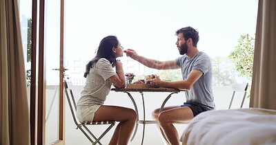 Buy stock photo Breakfast, feeding and romance with couple on balcony of home together for bonding or love. Eating, hunger and morning with happy people outdoor at apartment for anniversary, connection or honeymoon