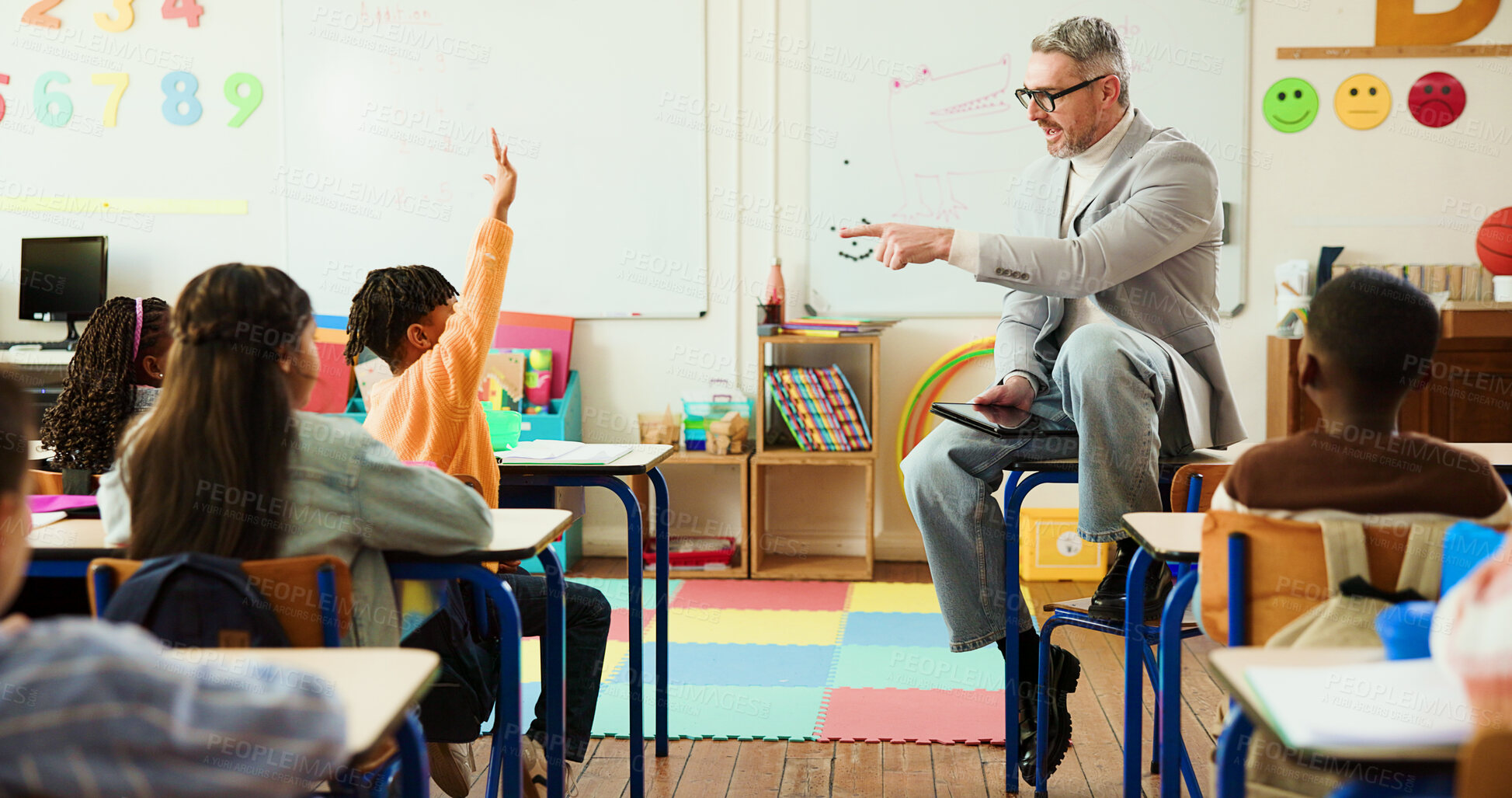 Buy stock photo Hand raised, classroom and educator with kids for learning, education or development with storytelling. Teaching, technology and male teacher with students for question in elementary school with help