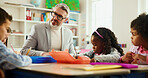Education, learning or study with children and teacher at desk in classroom for child development. Future, growth and teaching students with educator man in elementary school class for lesson