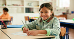 Happy, writing and portrait of girl in classroom with confidence for education, learning or growth. Smile, student and face of kid at elementary school for quiz, test or assessment at campus.