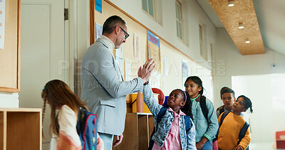 Buy stock photo Teacher, children and high five greeting at school for welcome to classroom for education. Encourage, smile or group of kids with happy man for learning, scholarship and morning in hallway at academy