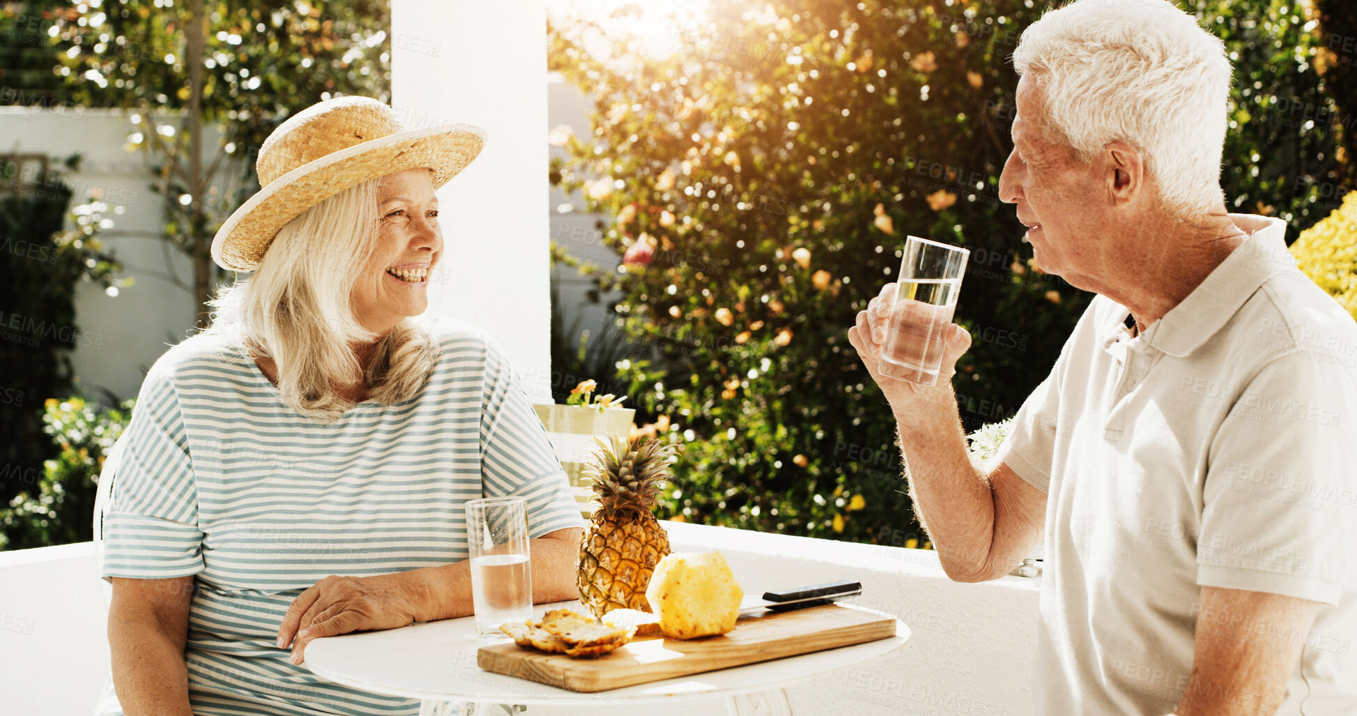Buy stock photo Senior, happy couple or eating with breakfast in garden for healthy snack, water or pineapple. Elderly, man and woman with smile, drink or natural organic fruit for retirement together in backyard