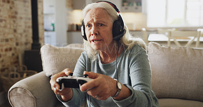 Buy stock photo Senior woman, competitive and playing with video games on sofa for online entertainment in home. Worry, elderly gamer or female person with concern, control or headphones for arcade console in house