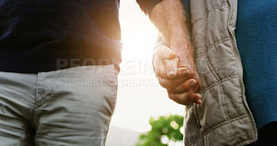 Buy stock photo Senior couple, holding hands and walking with love in garden for commitment, loyalty or trust. Closeup, elderly man or woman with lens flare in outdoor nature for bonding, safety or security together