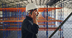 Man, phone call and discussion at storage plant, inspection and report with back at industrial warehouse. Person, smartphone and feedback with contact, talk or review for supply chain management