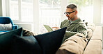 Tablet, freelancer and mature man in home to review news, article or reading online. Technology, remote work and journalist in living room to check email for headline, story and research on internet