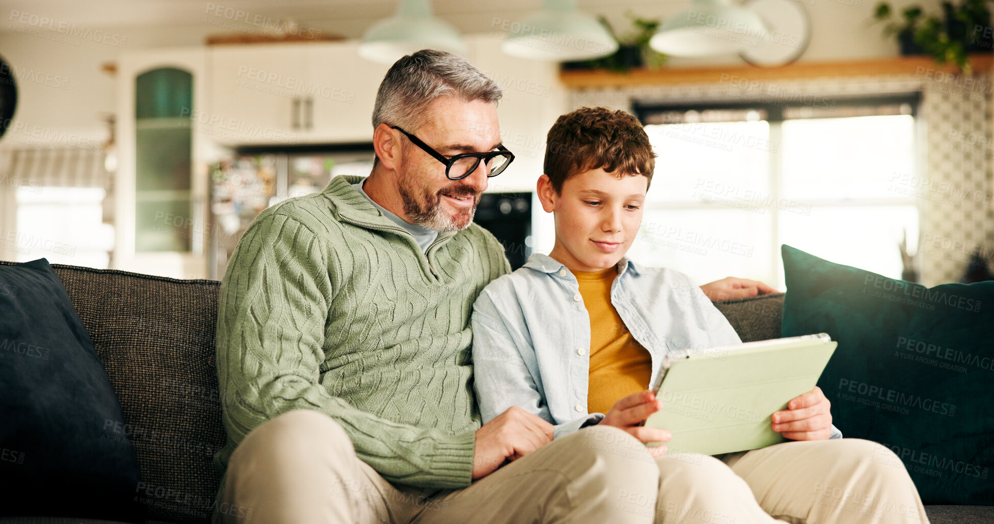 Buy stock photo Home, father and boy on couch, tablet and bonding together with online game, relax and learning. Help, family or dad with son, support and parent with tech, social media or app with child development