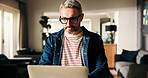 Laptop, remote work and mature man in home to review news, article or report online. Computer, journalist and freelancer in living room to check email for headline, story and research on internet