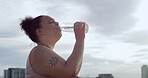 Woman, plus size and drinking water in fitness for weight loss, diet or healthy nutrition in city. Tired, female person or thirst with mineral liquid for workout break, rest or hydration in town