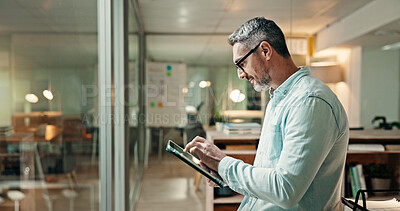 Buy stock photo Design, night and tablet with business man in workplace for overtime planning or research online. App, creative and reading with graphic designer in glass office for evening deadline or launch