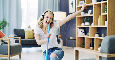 Buy stock photo Girl, broom and singing with headphones in home, cleaning and happy with streaming in living room. Woman, excited and listen to music with audio subscription, performance or voice for chores at house