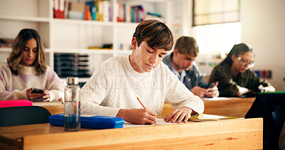 Buy stock photo Boy, student and writing with books in classroom for higher education, learning or development. Male person, teenager and studying with textbooks in class for knowledge, assessment or test in school