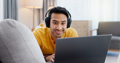 Buy stock photo Man, laptop and headphones on sofa for video, social media and movie streaming or website in home. Relax, internet audio and male person on couch with technology, break and watching film on app