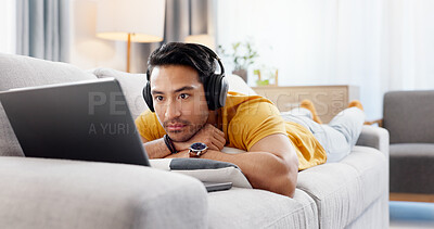 Buy stock photo Man, laptop and headphones on sofa for movie, social media and video streaming or website in home. Relax, internet audio and male person on couch with technology, break and watching film on app