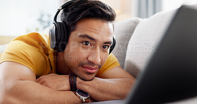 Buy stock photo Relax, laptop and watching with man on sofa for streaming service, headphones and film. Movie subscription, media website and home cinema app with person in living room of apartment for online video