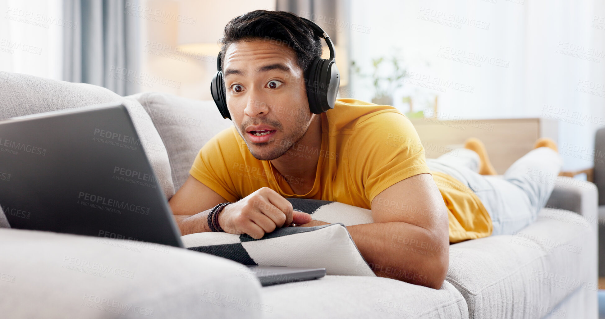 Buy stock photo Headphones, laptop and wow with man on sofa in living room of home for online streaming subscription. Computer, relax and surprise with person in apartment for break, media entertainment or movie