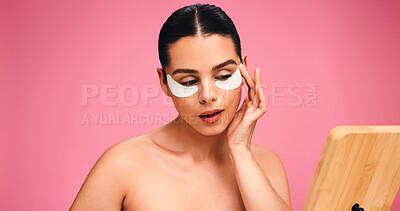 Buy stock photo Woman, mirror and eye mask for skincare in studio for dark circle, reduce puffiness and hydration. Person, cosmetic patches and mockup space for beauty, collagen benefits and shine on pink background