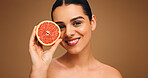 Portrait, woman and grapefruit with smile for beauty, natural skincare and facial glow. Happy, person and fruit for collagen, vitamin c and organic ingredients of treatment shine in studio background