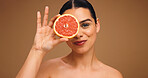 Portrait, woman and grapefruit with smile for skincare, natural beauty and facial glow. Happy, person and fruit for collagen, vitamin c and organic ingredients of treatment shine in studio background
