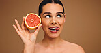 Woman, tongue out and grapefruit for skincare, playful with organic space or vitamin C in studio. Person, thinking and dermatology with fruit for healthy skin, mockup and expression on background
