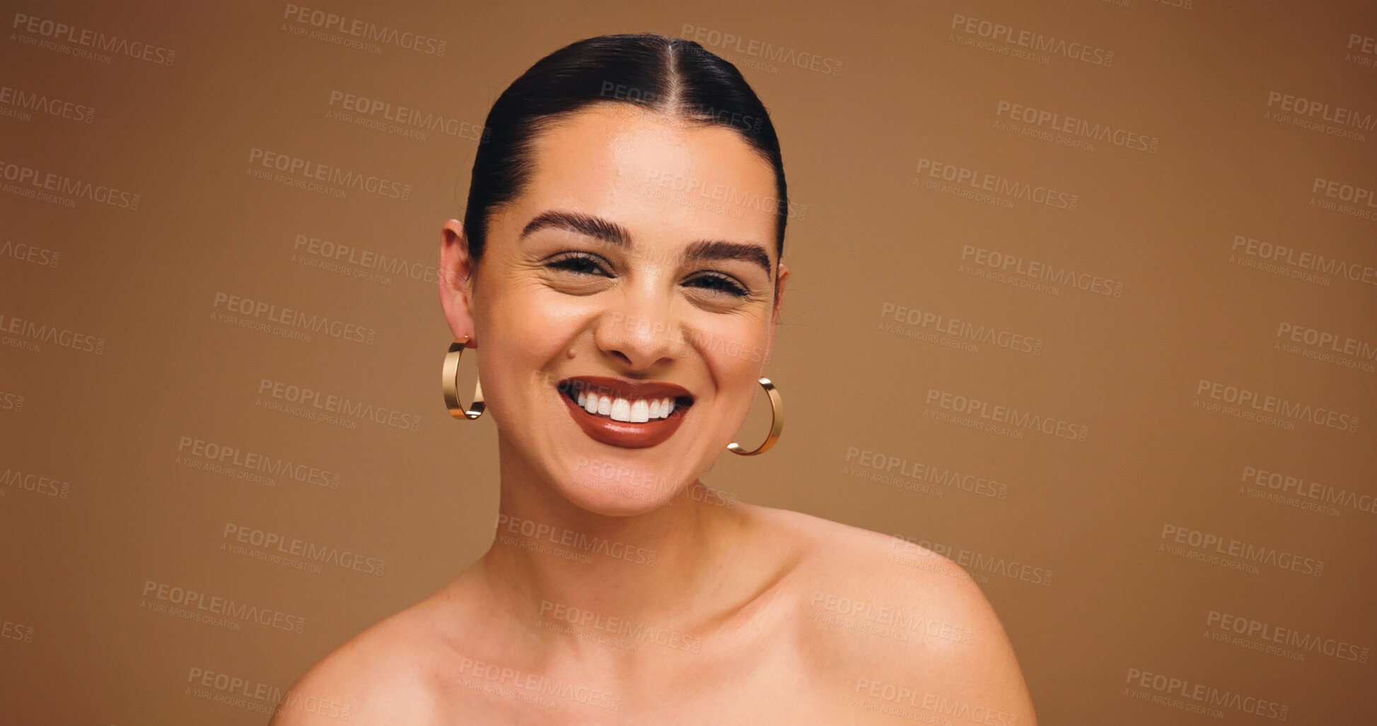 Buy stock photo Makeup, earrings and happy woman in studio for aesthetic, glow and shine on brown background space. Beauty, ear jewelry and model with lipstick cosmetics, face transformation and portrait with change