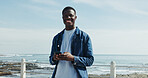 Portrait, smile and black man at beach with phone, space and university student on break. Happy, positive and African person at ocean with technology, fresh air and mobile app for college schedule.