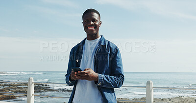 Buy stock photo Portrait, smile and black man at beach with phone, space and university student on break. Happy, outdoor and African person at ocean with technology, fresh air and mobile app for college website.
