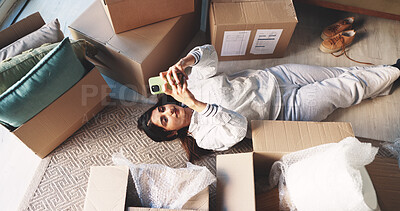 Buy stock photo Woman, new home and phone with boxes on floor, texting or relax on break, moving or above in lounge. Person, chat and smartphone on carpet with mobile app, post or social media for property investing