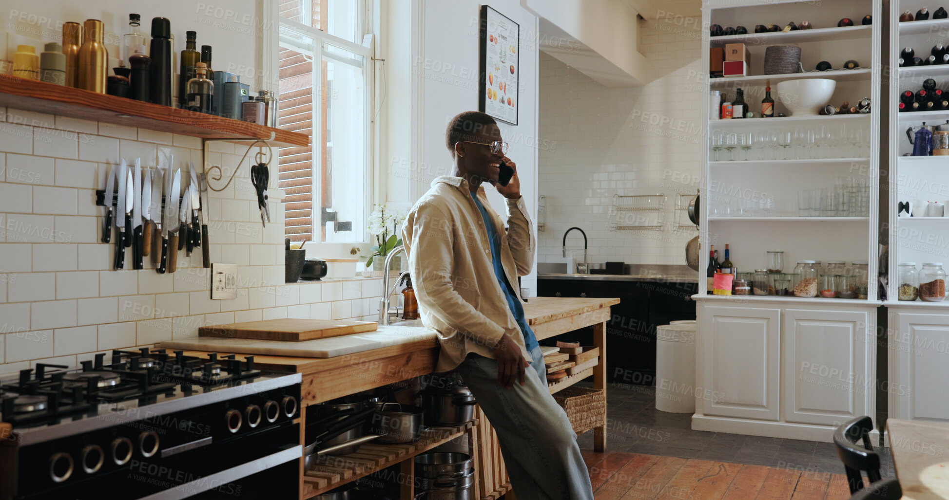 Buy stock photo Talk, phone call and happy black man in kitchen for chat, gossip and communication with contact. African person, smile and conversation with mobile for news, update or feedback for connection in home