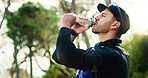 Thirsty, athlete or man in nature with water, active or fitness in wellness for outdoor exercise. Training, cardio and healthy person with glasses, sportswear and hydration in park for body care.