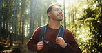 Happy man, hiking and trees with backpack in forest for outdoor adventure in wilderness. Male person, hiker or smile with bag or sunshine for trekking journey, exploration or sightseeing in nature