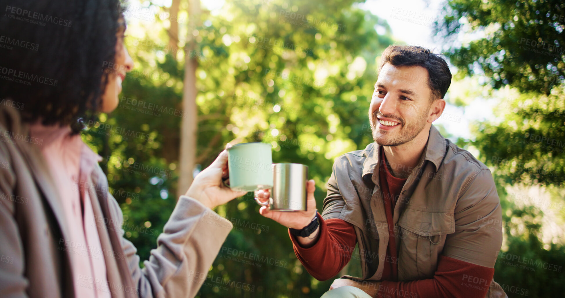 Buy stock photo Couple, hiking and coffee break in woods with toast, happy and success on tourism adventure in summer. Man, woman and travel with interracial love, tea cup or cheers on holiday for trekking in forest