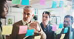 Man, glass wall and sticky note with team, talk and brainstorming for project at media company. Business people, mature leader and startup for discussion, planning or collaboration at creative agency