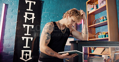 Buy stock photo Neon, tablet and thinking with man in tattoo parlor for artistic design or creative planning. App, ideas and small business with designer person in studio for ink or process of body art development