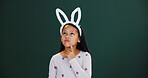 Bunny ears, Easter and thinking with girl child in studio for holiday ideas or planning. Choice, decision and space with thoughtful kid isolated on green background for vacation selection or vision