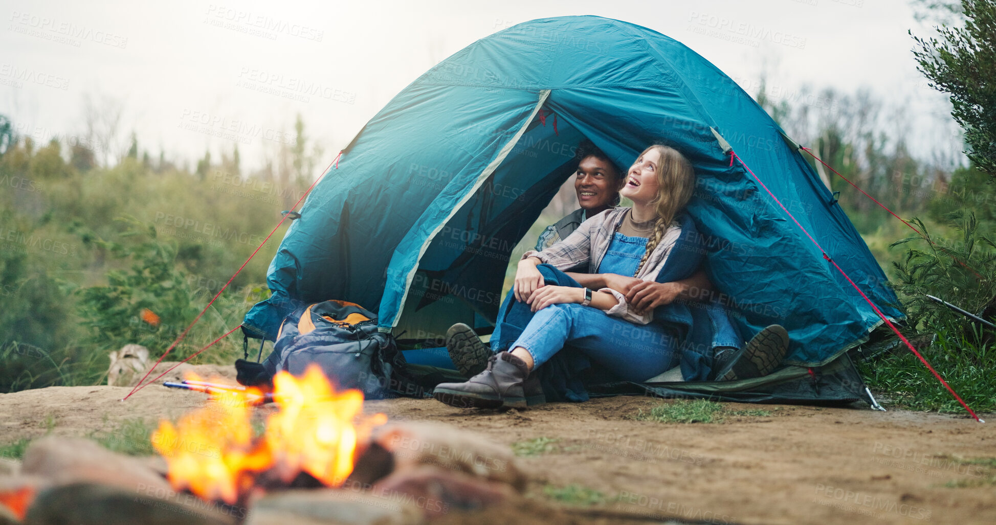 Buy stock photo Happy couple, tent and relax with fire for camping, outdoor vacation or holiday together in nature. Man, woman or love with smile, flame or shelter for safety, security or protection in wilderness