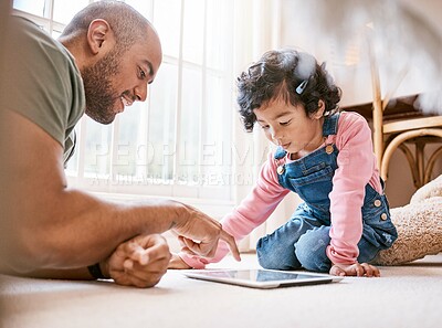 Buy stock photo Shot of a little girl using a digital tablet with her father at home