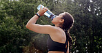 Fitness, woman and water in nature for health, wellness or exercise break with hydration liquid. Bottle, person or thirsty runner with drink outdoor for workout recovery, minerals or sports nutrition