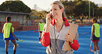 Coach, hockey turf and woman with phone call for match organization, conversation and event info.Planning, mobile and sport trainer with clipboard on field, game arrangement and local league opponent