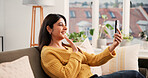 Cellphone, video call and woman on sofa in home with communication, greeting and online conversation. Happy, waving and female person with phone for virtual discussion with networking in living room.