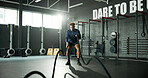 Man, battle rope and workout in gym for cardio, exercise and body building for fitness. Intense routine, muscle and wellness with power for strength training, weight equipment and bicep challenge