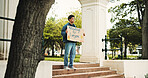Man, student and campus with poster for protest, education or knowledge of human rights in park. Male person, scholar or academic activist with sign or cardboard for learning development of humanity