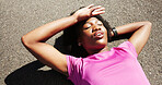 Tired, fitness and above of black woman in road for rest, recovery and relax for exercise outdoor. Sports, lying and person with fatigue in town for health, wellness and break for workout or training