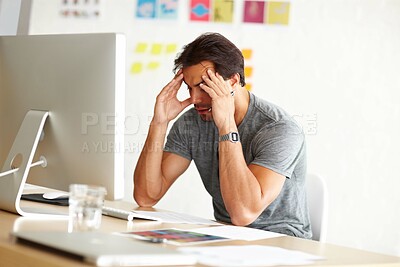 Buy stock photo An overwhelmed man sitting at an office desk with his head rested against hands