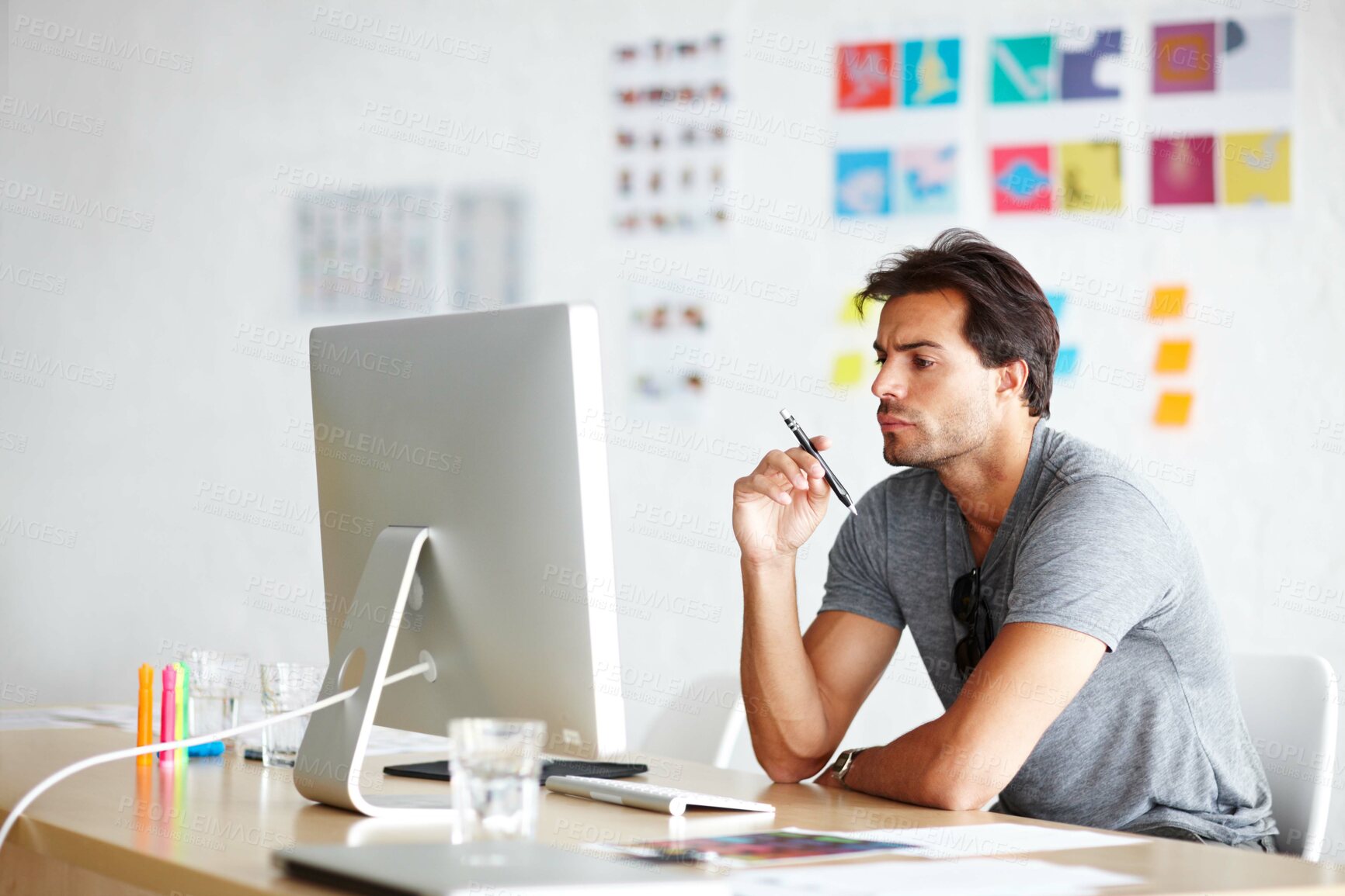 Buy stock photo A handsome young man looking bored in front of his computer