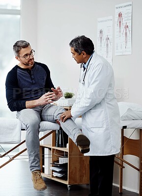 Buy stock photo Shot of a confident mature male doctor doing a checkup on a patient inside of a hospital during the day