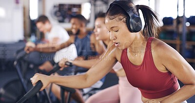 Buy stock photo Headphones, gym and woman on stationary bike for exercise, training and cardio workout for health. Sports club, sweat and people on machine for cycling, wellness or fitness with music, radio or audio