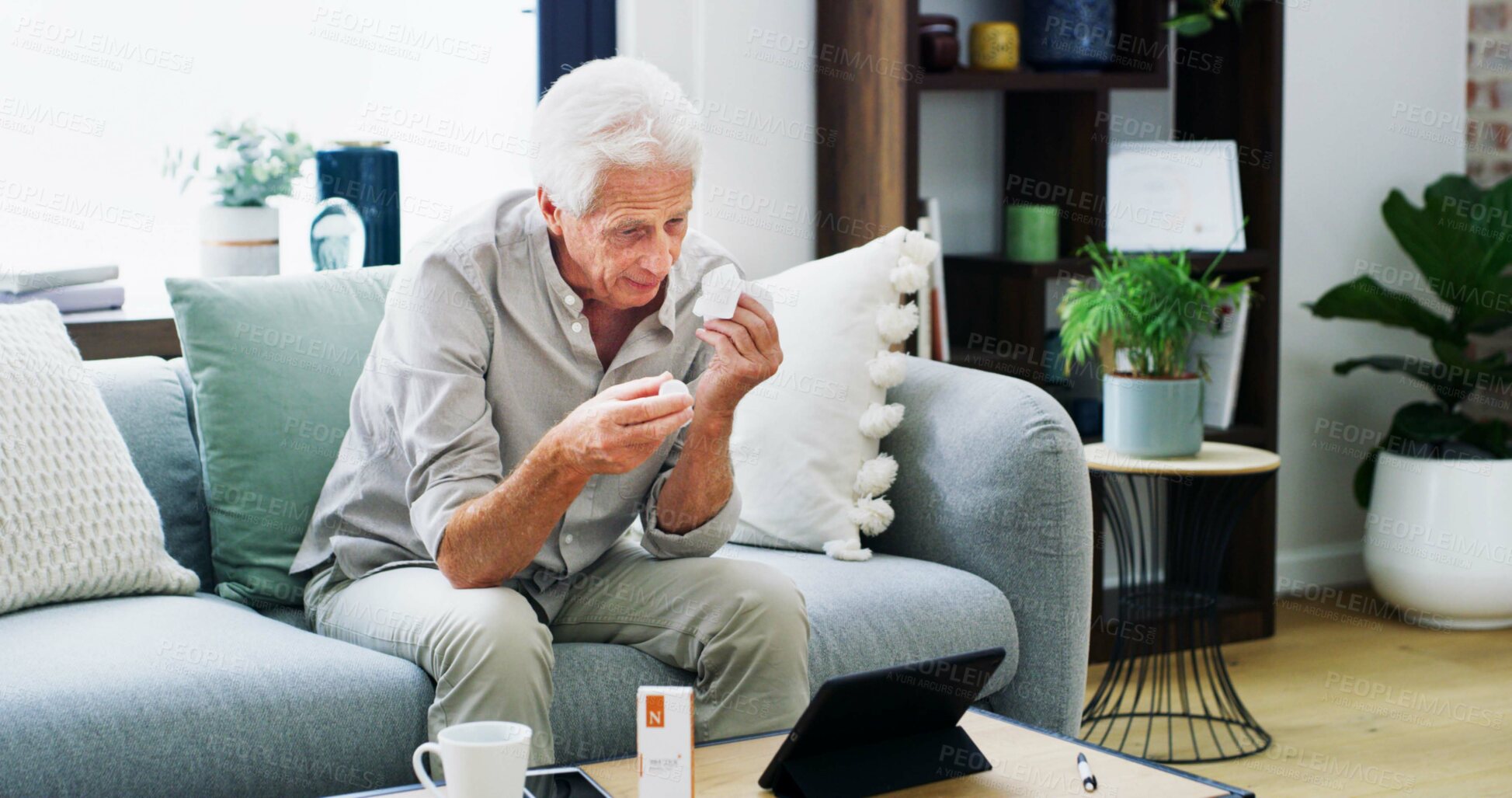 Buy stock photo Medication, video call or old man on sofa with tablet, pill research or telehealth check for dose. Healthcare, online chat or male person in house with tech, reading label and wellness in retirement.